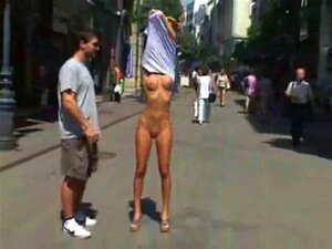 Fille debout totalement nue dans une rue publique. Fille debout