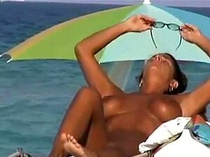 MILF à gros seins bronzant à la plage nude